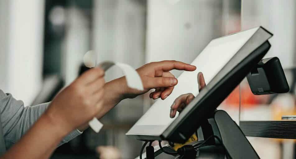 Hands using a touchscreen point-of-sale system and holding a receipt, highlighting financial management