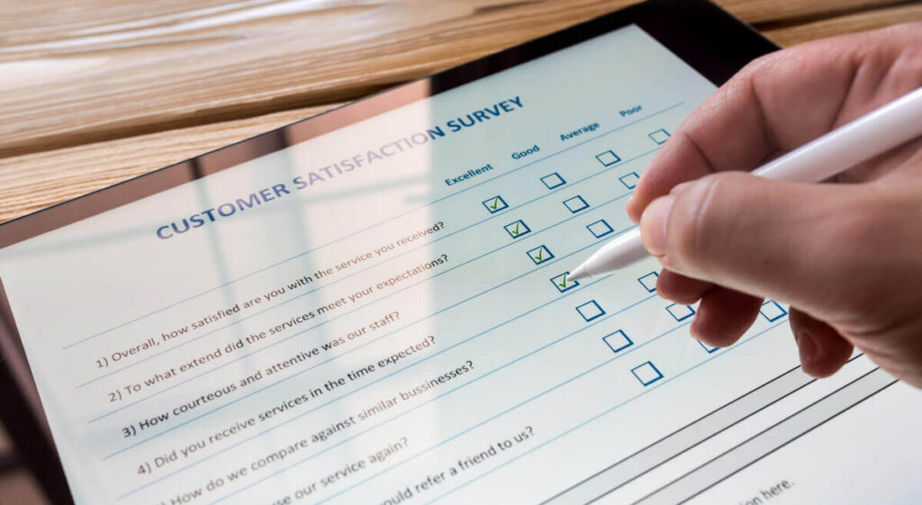 Hand using a stylus to fill out a digital customer satisfaction survey on a tablet