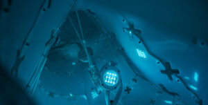 Blue-lit robotic arm with LED lights, surrounded by glowing patterns, symbolizing AI and automation