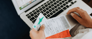 Hand holding a credit card and receipts over a laptop, illustrating an OCR receipt scanner
