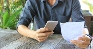 Person using a smartphone and holding a receipt, likely for OCR receipt capture