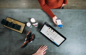 Overhead view of a customer paying with a smartphone at a retail counter with a POS tablet