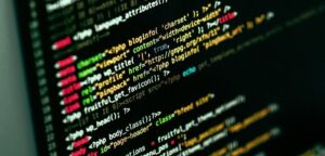 Close-up of a computer screen displaying lines of colorful code, likely PHP, on a dark background