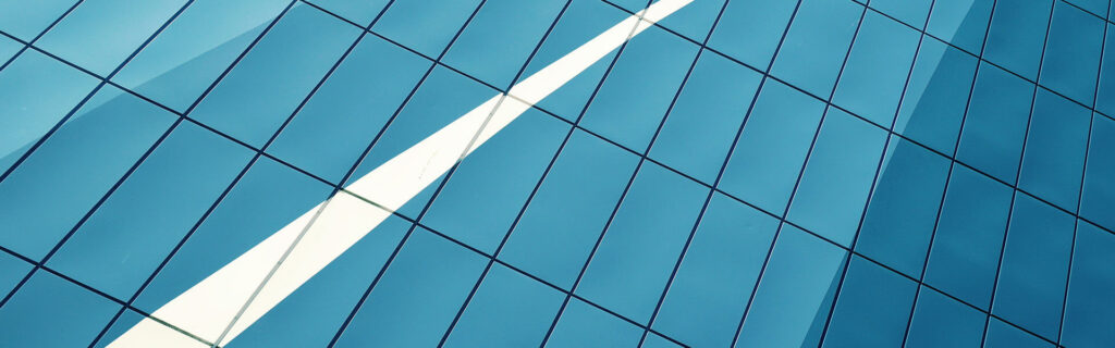 Blue glass facade of a building with a diagonal white stripe, resembling a checkmark
