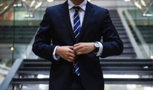 Man in a suit and striped tie buttoning his jacket, representing professionalism and digital receipts
