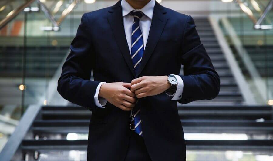 Man in a suit and striped tie buttoning his jacket, representing professionalism and digital receipts