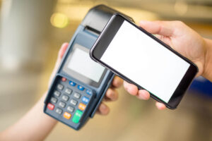 Hand holding a smartphone over a payment terminal for a contactless transaction
