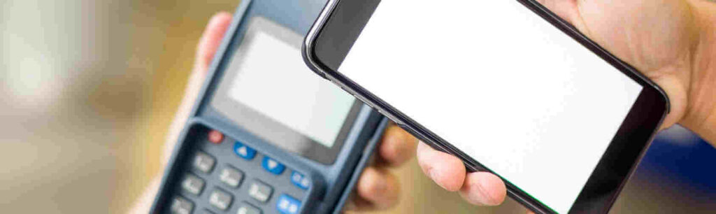 A person holding a smartphone with a blank screen near a payment terminal