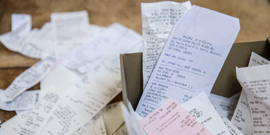 A pile of paper receipts, some crumpled, some in a box, ready for OCR scanning