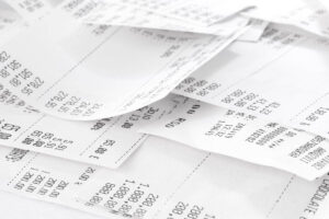 A pile of white paper receipts with black text, showing various prices and items