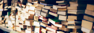 Stacks of old books, some open, some closed, filling the frame